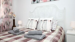 A neatly made bed with a patterned bedspread, two pillows with striped designs, and a rolled-up towel on the bed. - Los Boliches apartment - central location (Fuengirola)