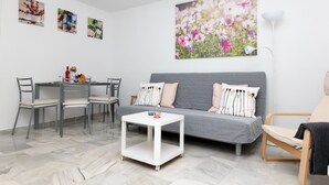 A modern living room with a grey sofa, a white coffee table, and a dining area with chairs and a table. - Los Boliches apartment - central location (Fuengirola)