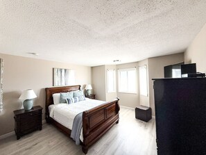 Un dormitorio con cama de madera, mesitas de noche, cómoda y ventana con persianas.