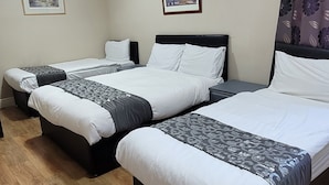 Habitación de hotel con dos camas, suelo de madera y dos cuadros enmarcados en las paredes.