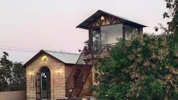A small, single-story building with a sloped roof and a staircase leading to a balcony. - Rain Forest Gir Resort (Talala)