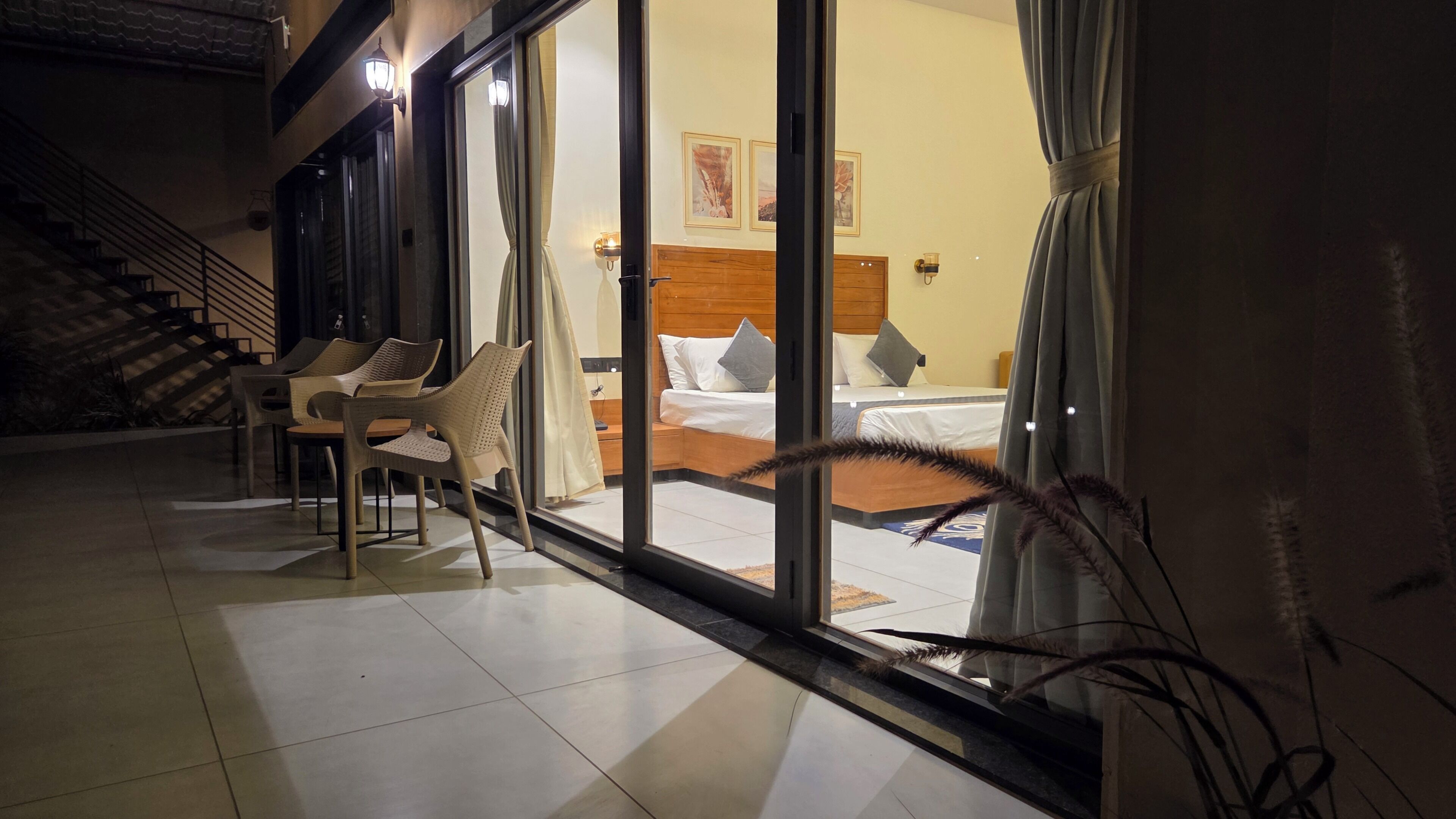 Una habitación de hotel con cama, mesita de noche, una silla y ventana con cortinas.