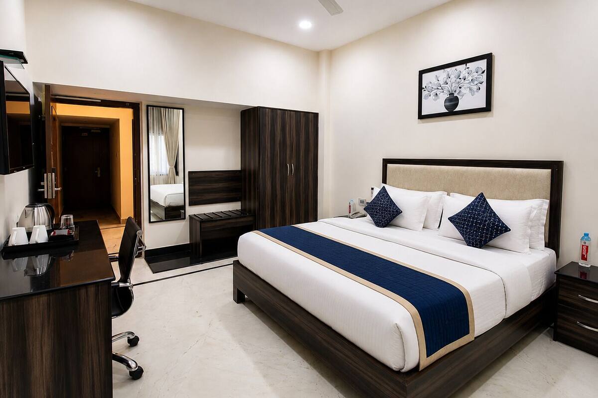 Habitación de hotel con cama, mesita de noche, escritorio, silla, armario y ventilador de techo.