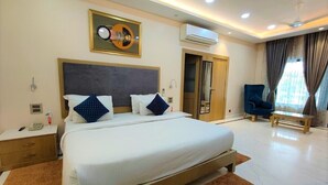 A modern hotel room with a large bed, a desk, a chair, and an air conditioning unit. - JASWANT VILAS A BOUTIQUE HOTEL (Prayagraj)