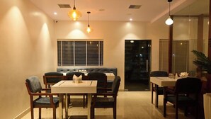 A dining area with a table and chairs, a sofa, and pendant lighting. - JASWANT VILAS A BOUTIQUE HOTEL (Prayagraj)