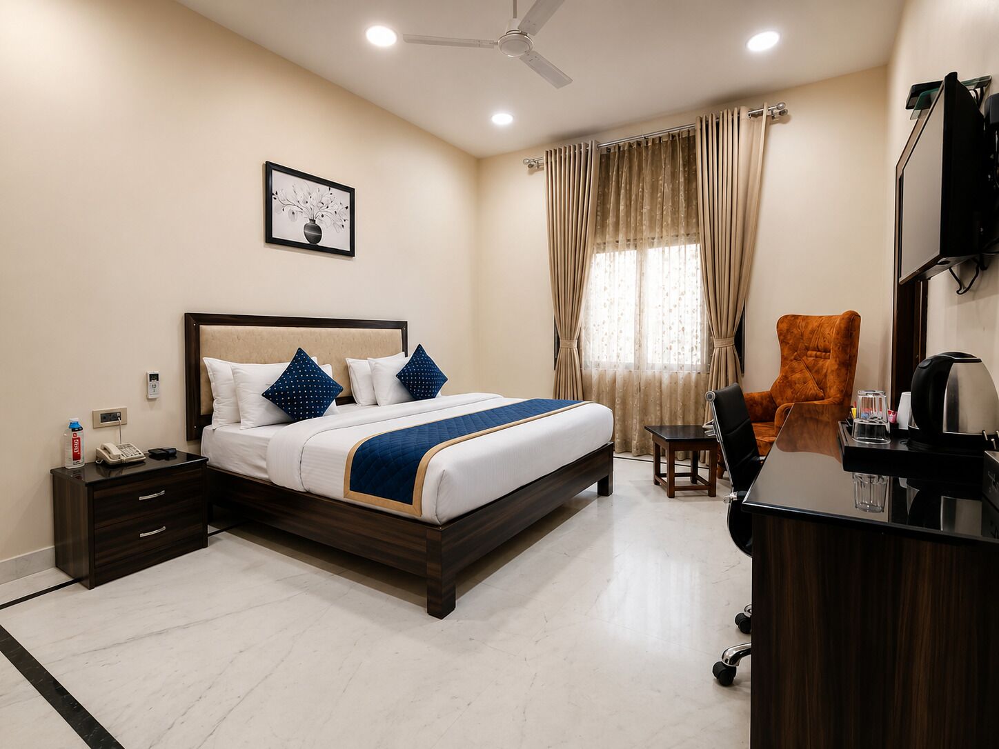 A hotel room with a bed, bedside table, chair, desk, and a ceiling fan.