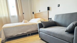 Ein Hotelzimmer mit einem Bett, einem grauen Sofa und einem Nachttisch.