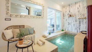 A modern bathroom with a freestanding bathtub, a large mirror, and a wicker sofa. - ClickSardinia Villa Tramonto by the beach with path to the sea (sorso)