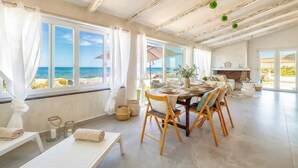 A spacious room with a dining area, large windows with ocean views, and a fireplace. - ClickSardinia Villa Tramonto by the beach with path to the sea (sorso)