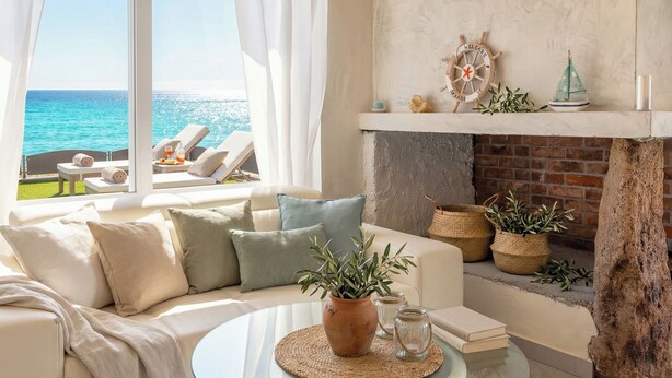 A modern living room with a glass coffee table, a sofa with cushions, a potted plant, and a fireplace with decorative items. - ClickSardinia Villa Tramonto by the beach with path to the sea (sorso)