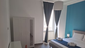 A hotel room with a bed, a desk, a chair, and a wardrobe. - At Home Gaeta Guest House (Rome)
