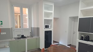 A modern kitchen with green cabinets, a built-in microwave, and a round wooden table with chairs. - At Home Gaeta Guest House (Rome)