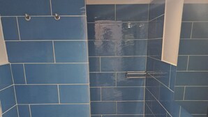 A bathroom with blue tiles, a white sink, and a wooden vanity. - At Home Gaeta Guest House (Rome)