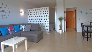 Ein modernes Wohnzimmer mit grauem Sofa, weißem Couchtisch und einer dekorativen Wandverkleidung.