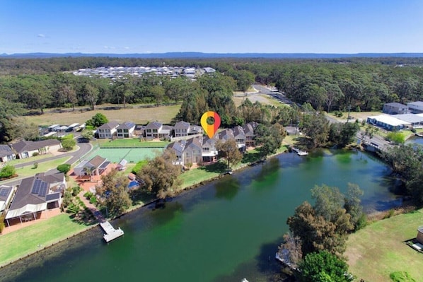 Vista aérea de una zona residencial con casas, un río y un campo deportivo.