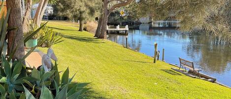 A well-maintained grassy area with a pond, benches, and a bridge.