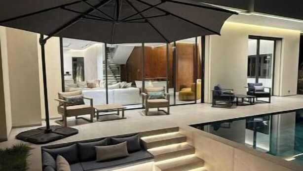 A modern outdoor living area with a built-in pool, seating, and a large umbrella. - Luxury golf villa with heated pool-near center (Marrakech)