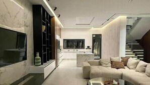 A modern living room with a sofa, coffee table, and built-in TV. - Luxury golf villa with heated pool-near center (Marrakech)