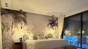 A modern bedroom with a large bed, a nightstand, a wall mural, and a view of the outdoors through a large window. - Luxury golf villa with heated pool-near center (Marrakech)