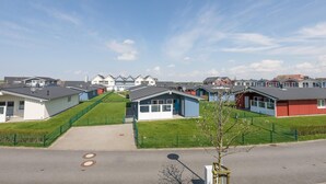 A row of modern, single-story houses with a central driveway leading to a gated entrance. - Holiday Home in Dagebull With Terrace (Dagebuell)