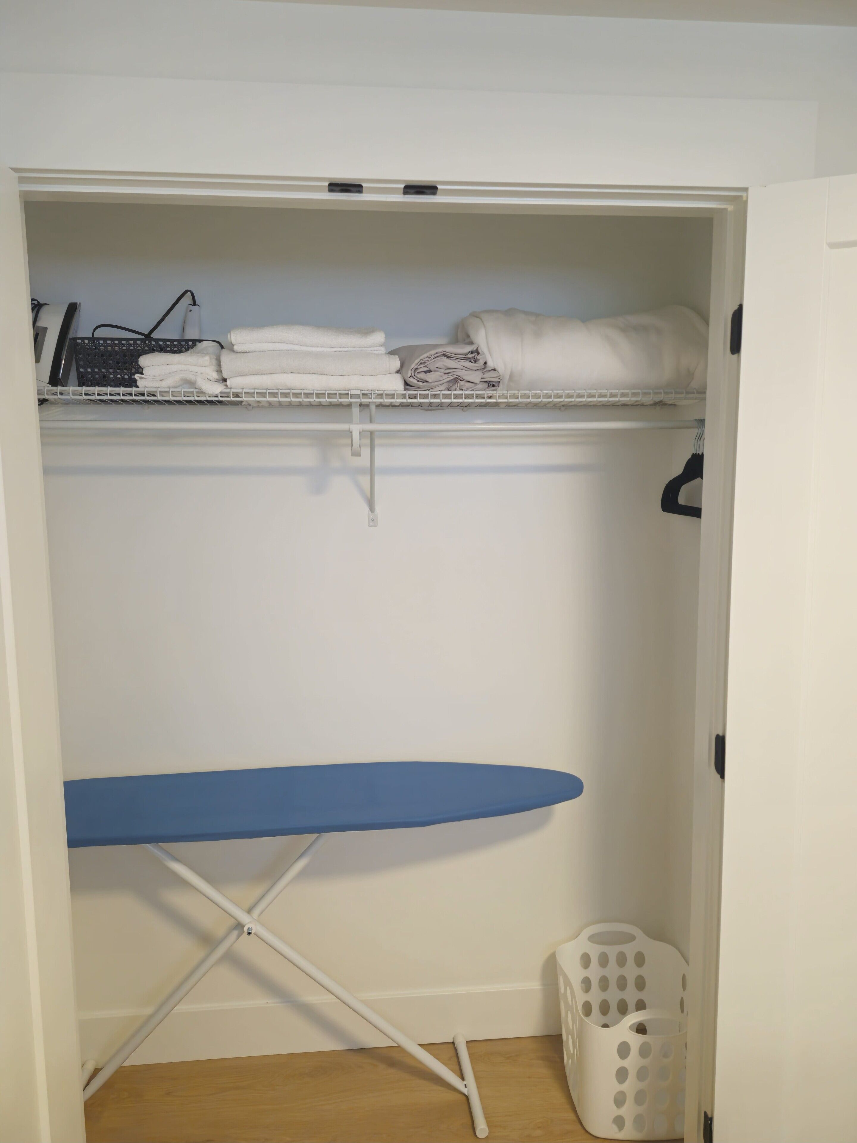 A closet with shelves holding folded towels and a laundry basket.