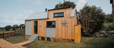 A wooden house with a small front porch, a window, and a door.