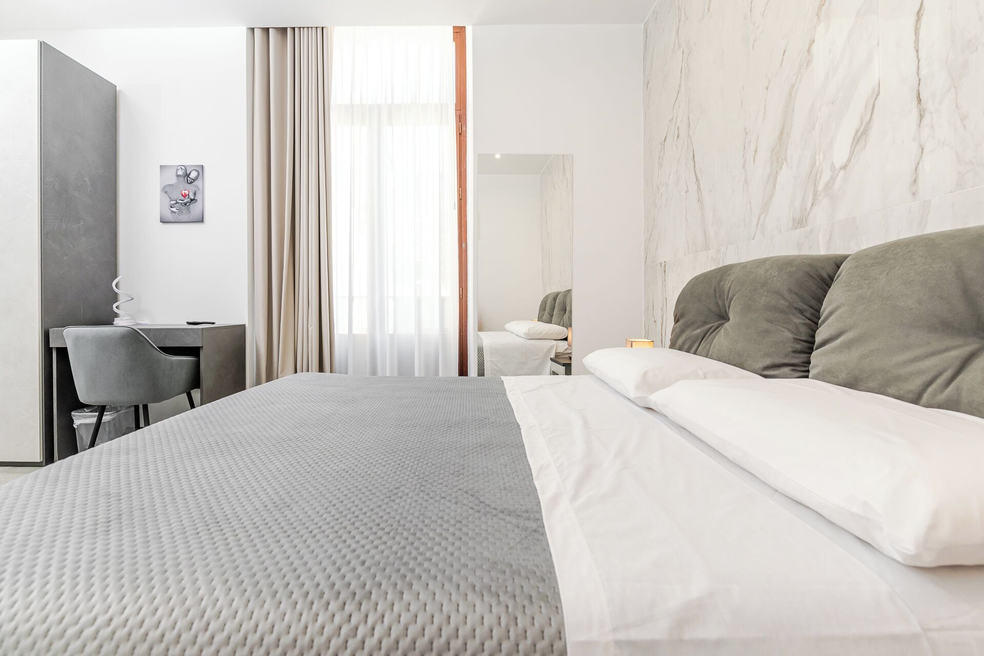 Une chambre d’hôtel moderne, dotée d’un grand lit, d’un bureau et d’une chaise.