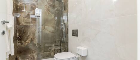 Un baño con ducha de vidrio, inodoro y lavamanos.