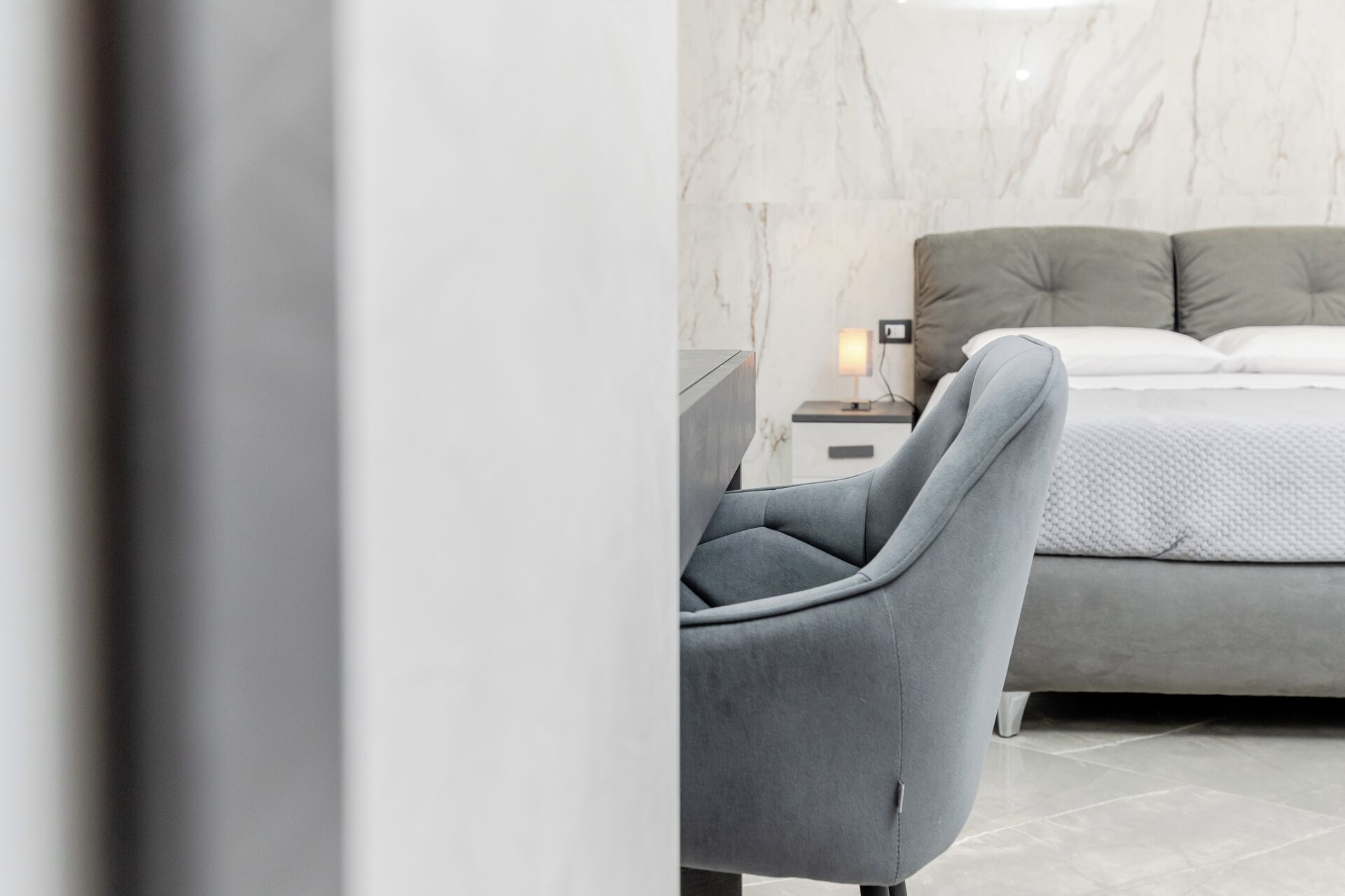 Un dormitorio moderno con una cama grande, una mesita de noche y una silla.
