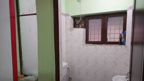 A small bathroom with a toilet, sink, and a window above the sink.