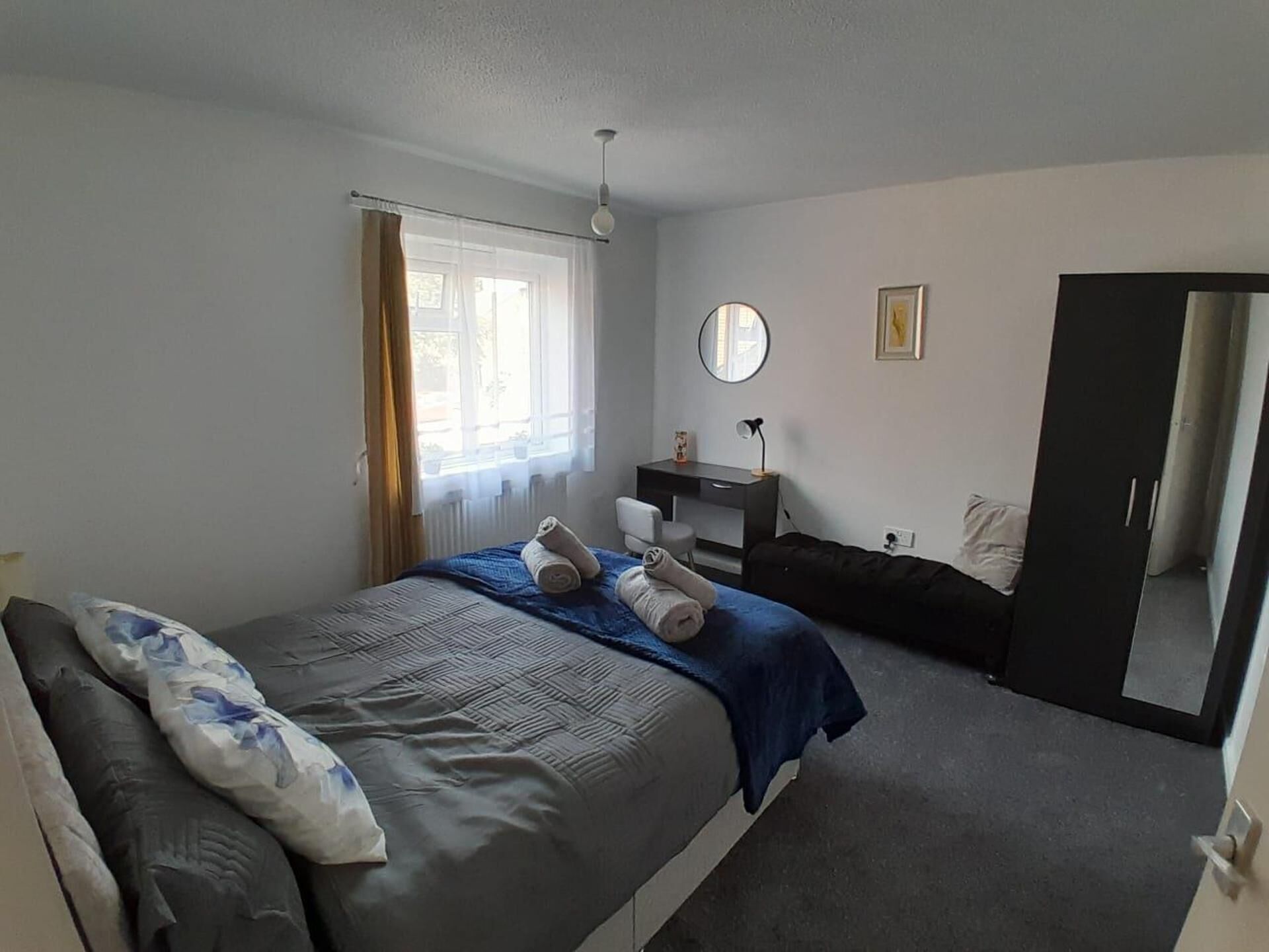 Una camera da letto con un letto, una scrivania, una sedia, uno specchio e un armadio.