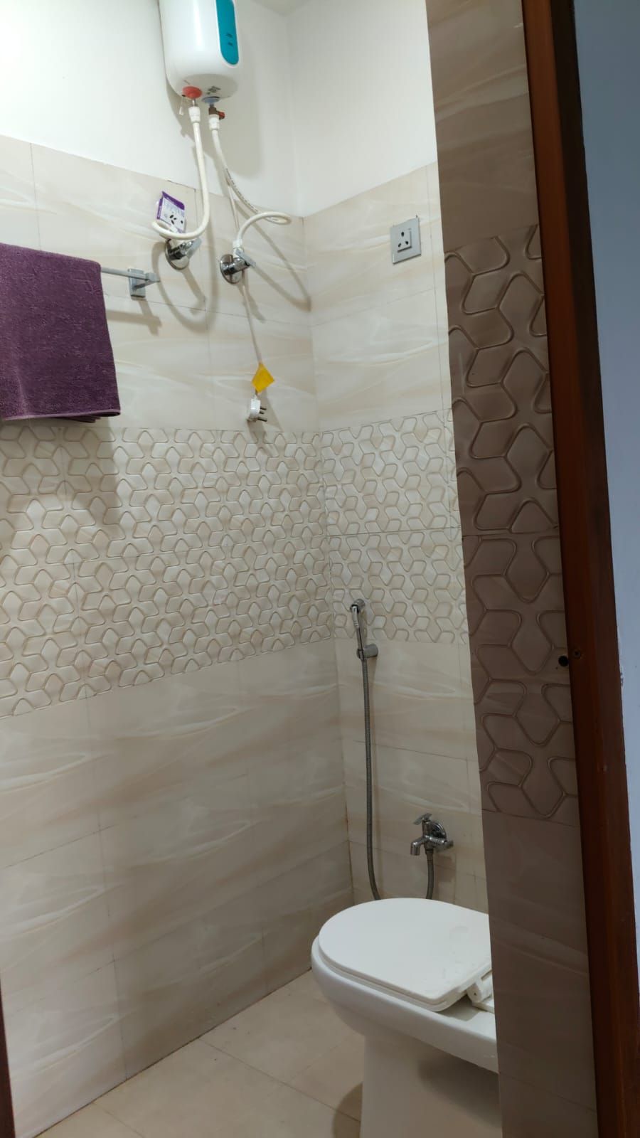 A small bathroom with a shower, toilet, and a towel rack.