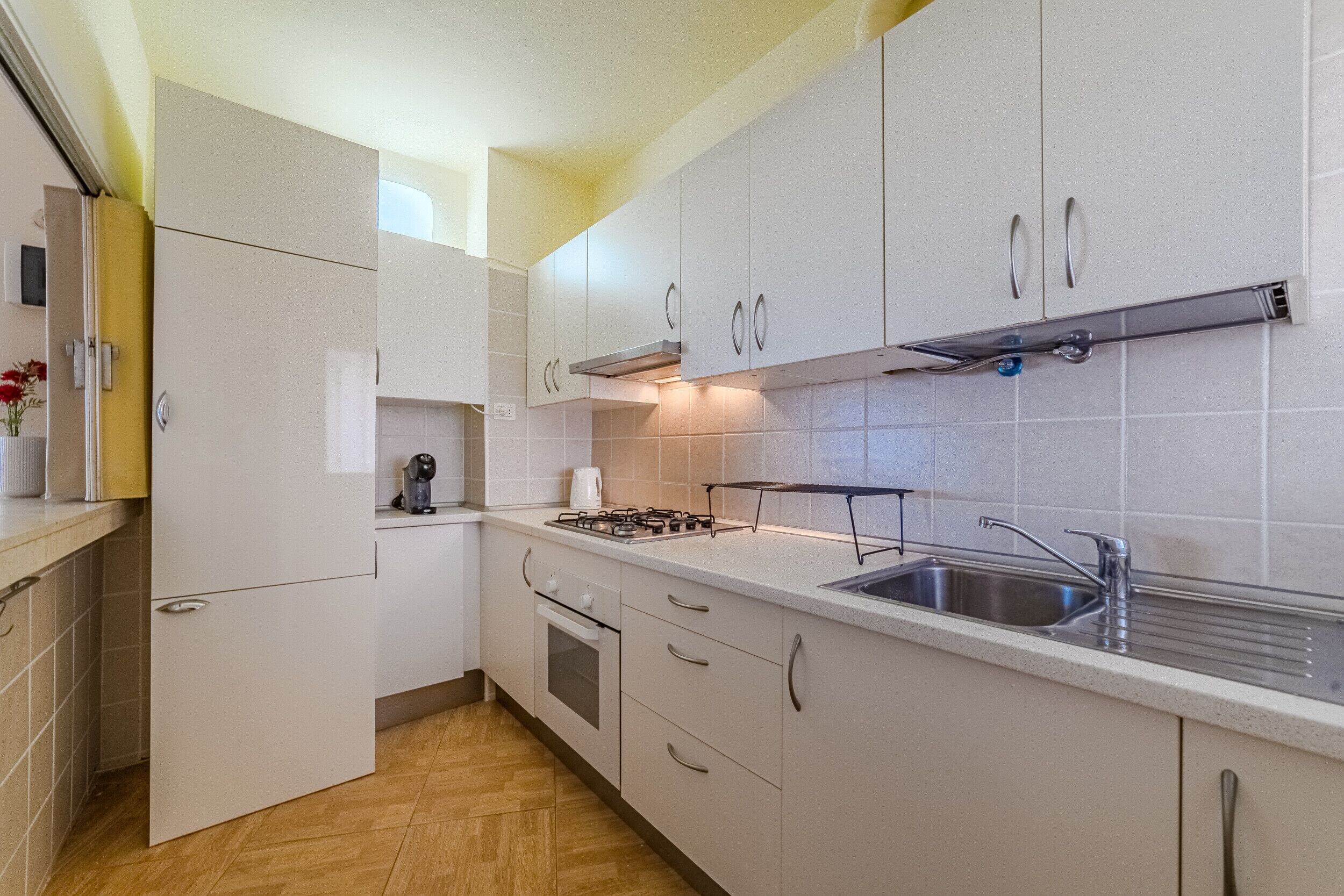 A modern kitchen with white cabinets, a stainless steel sink, and a gas stove.