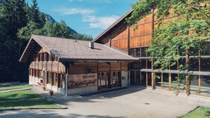 A modern building with a wooden facade and large windows, surrounded by greenery and mountains. - Wirie-Lodge in Diemtigen Holiday apartment on the Wiriehorn - Mountains & relaxation (Diemtigen)