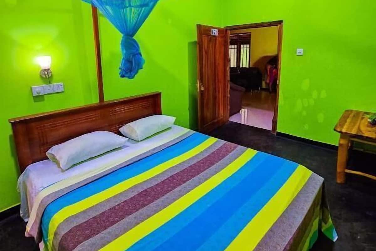 Una habitación con cama, ventilador de techo, mosquitero y una puerta que da a otra habitación.