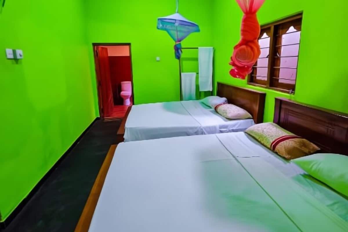 Una habitación con dos camas, una ventana y una puerta que da a un baño.