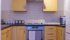 A kitchen with wooden cabinets, a stainless steel range hood, a built-in oven, and a microwave.