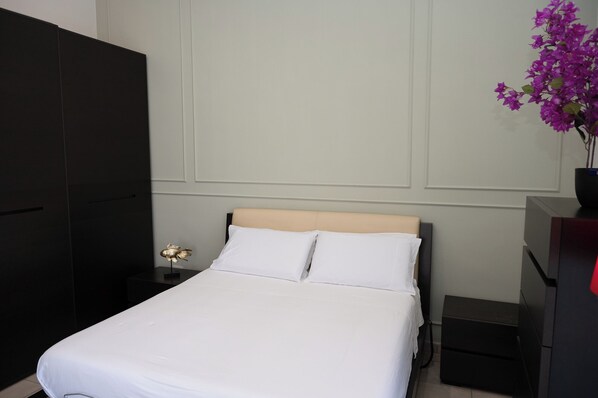 A neatly made bed with white linens, a wooden headboard, and a small bedside table with a lamp. - Costa d'Amare - Holiday House (Salerno)