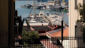 A marina with various boats docked, a crane, and a clear sky.
