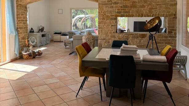 A spacious dining area with a stone wall, a dining table with chairs, and a dog on the floor.