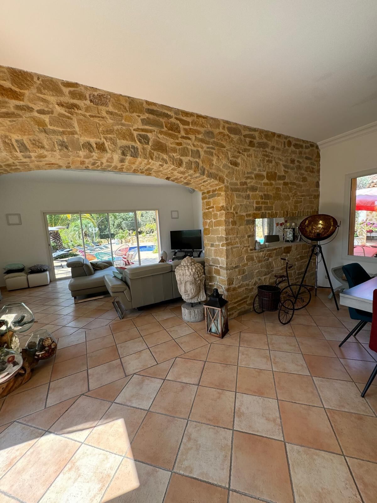 Uma sala de estar ampla com parede de pedra, um sofá, uma TV e um espaço de jantar com mesa e cadeiras.