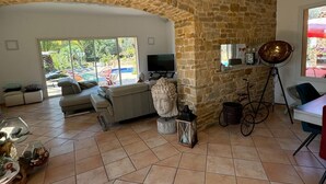 A spacious living room with a stone wall, a sofa, a TV, and a dining area with a table and chairs.