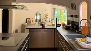 A modern kitchen with a central island, stainless steel appliances, and a large window providing natural light.