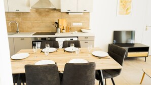 Une cuisine moderne avec un coin repas, équipée d’une cuisinière, d’un évier et d’un téléviseur.