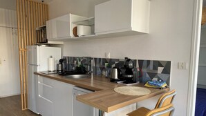 A compact kitchen with a wooden countertop, a coffee maker, a kettle, and a sink. There are two chairs and a small rug on the floor. - Center Reims Moderne with balcony and parking (Reims)