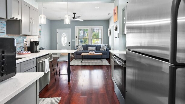 A modern kitchen with a central island, stainless steel appliances, and a dining area with a sofa.