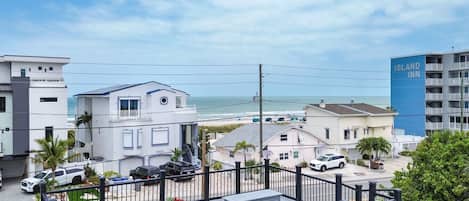 Un hotel frente al mar con vistas a la playa, una zona de estacionamiento y un edificio vecino.