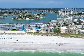 A coastal cityscape with a beachfront hotel, marina, and residential buildings. - Coastal Paradise at Nautilus: Walk to the Water (Treasure Island)