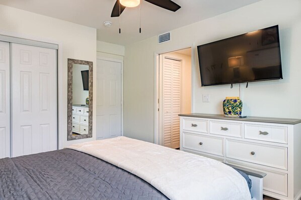 Un dormitorio con cama, cómoda, televisor y espejo.