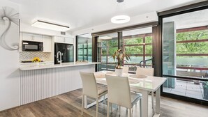 Une cuisine moderne dotée d’un îlot central, de meubles blancs et d’une grande fenêtre donnant sur un paysage verdoyant.